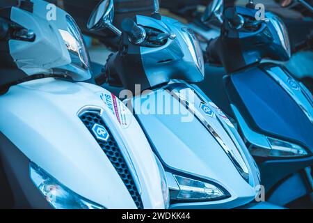 Primo piano di un nuovissimo scooter parcheggiato di fila. Scooter elettrici a noleggio. Fila di scooter elettrici parcheggiati in città Foto Stock