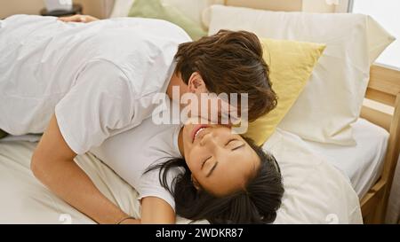 Coppia interrazziale che condivide un momento tenero insieme in camera da letto, mostrando affetto e amore al chiuso. Foto Stock