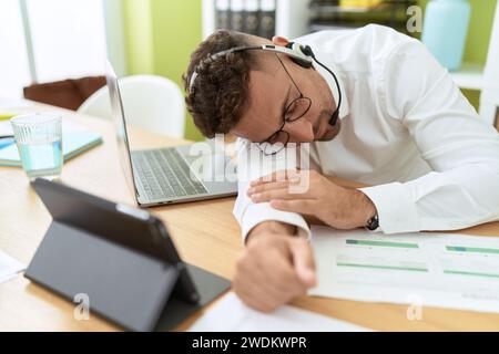Giovane uomo ispanico agente call center che lavora stanco dormire in ufficio Foto Stock