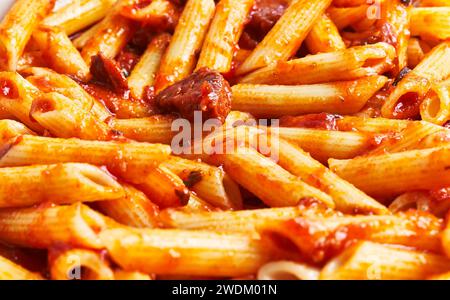 Primo piano di penne in salsa di pomodoro con erbe aromatiche, perfetto per i concetti culinari della cucina italiana. Foto Stock