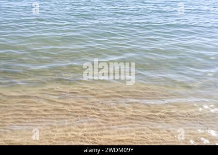 Le acque limpide bagnano dolcemente le spiagge sabbiose di una spiaggia tranquilla, assente da qualsiasi persona. Foto Stock