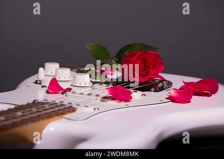 Red Rose e petali di rosa su White Electric Guitar Foto Stock