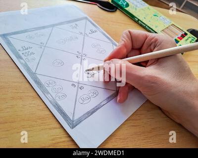 La mano di una donna riempie un grafico astrologico dell'astrologia Jyotish dell'antica India Foto Stock