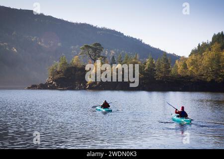 Uomo e donna in kayak su un lago nelle Highlands scozzesi in autunno. Glen Affric, Scozia, Regno Unito. Nessun volto riconoscibile. Foto Stock