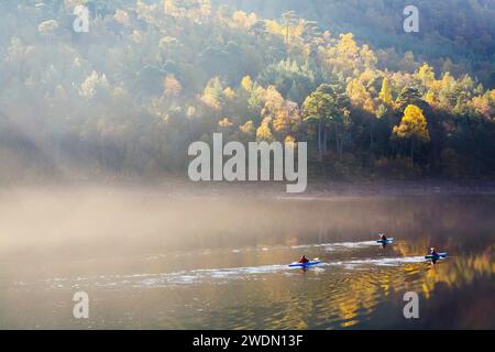 In autunno, le persone fanno kayak su un lago nelle Highlands scozzesi. Glen Affric, Scozia, Regno Unito. Nessun volto riconoscibile. Foto Stock