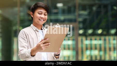 Giovane asiatico assistente manager tenendo appunti Foto Stock