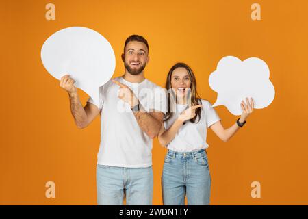 Felice coppia millenaria europea regge con gioia bolle di discorso, simboleggiando una conversazione vivace Foto Stock