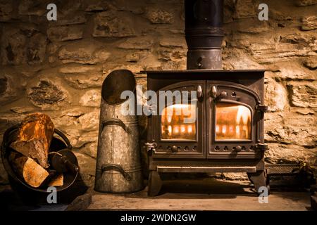 Stufa tradizionale a legna o a legna in un vecchio caminetto in pietra, Regno Unito Foto Stock