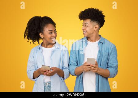 Una giovane donna e un uomo, entrambi sorridenti e guardarsi l'un l'altro, hanno uno smartphone Foto Stock