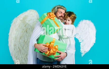 Buon San Valentino. Bambino piccolo e uomo barbuto con ali d'angelo con confezione regalo di San Valentino. La festa del padre. Il bambino abbraccia suo padre. Padre in Foto Stock