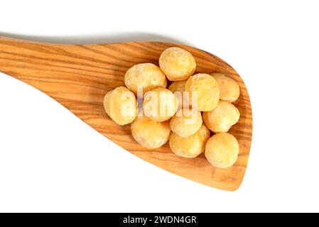 Noci di macadamia su un cucchiaio di legno su sfondo bianco Foto Stock