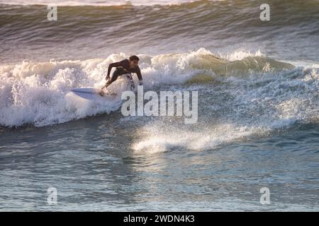 Giovane surfista con muta che si gode grandi onde. Foto Stock