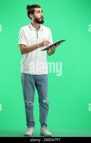 Un uomo, a tutta lunghezza, su sfondo verde, scrive Foto Stock