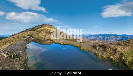 Piccolo lago pittoresco con riflessi nuvolari sul Monte Strymba. Bella giornata d'autunno in Carpazi Montagne vicino al villaggio di Kolochava, Transcarpat Foto Stock