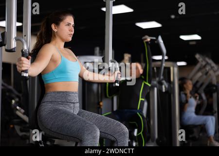 Ragazza giovane che esegue esercizi di petto in macchina farfalla Foto Stock