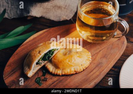 Pasticceria al forno con erba cipollina e funghi con tazza di tè verde su vassoio di legno Foto Stock