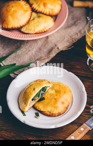 Dolci al forno ripieni di erba cipollina siberiana e funghi su piatto bianco Foto Stock