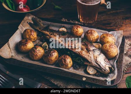 Pesce intero cotto con Sorrel e patate novelle su foglio di cottura Foto Stock