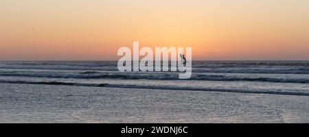 Kite surfer nell'aria in silhouette al cielo rosso al tramonto a Essaouira, Marocco, 21 gennaio 2024 Foto Stock