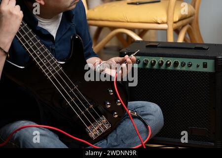 uomo latino che collega un basso elettrico ad un amplificatore, selflearner Foto Stock