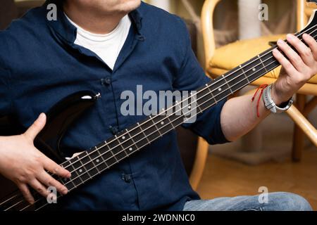 uomo latino che impara a suonare bassi elettrici a casa, da vicino Foto Stock