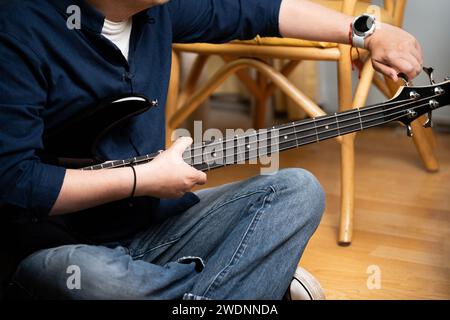 uomo latino che impara a suonare bassi elettrici sintonizzandolo Foto Stock
