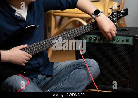 uomo latino che impara a suonare la sintonizzazione elettrica dei bassi dell'amplificatore Foto Stock