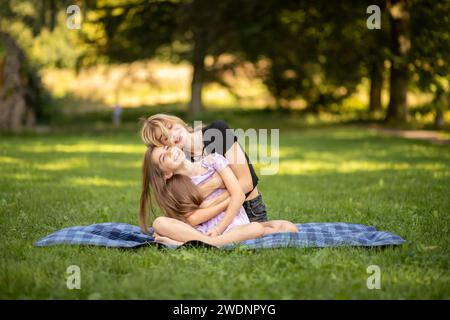 Madre e figlia che abbracciano e ridono a un picnic. Foto Stock