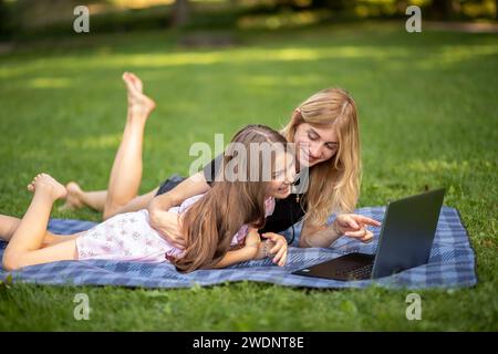 Madre e figlia sono felici di guardare un portatile nel parco. Foto Stock