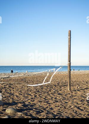 Rete da pallavolo caduta sulla spiaggia. Il concetto di inverno al resort del Mar Nero. Non c'è gioco. Il resort è fuori stagione. Pallavolo abbandonato Foto Stock