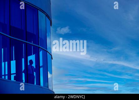 Executive a guardare fuori di windows nel suo angolo ufficio nel profondo del pensiero Foto Stock