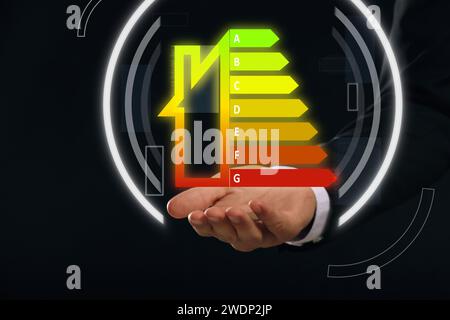 Efficienza energetica. Uomo con una valutazione colorata virtuale su sfondo nero, primo piano Foto Stock