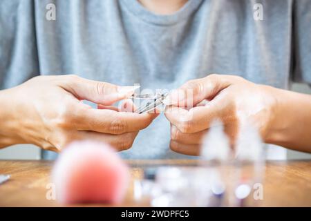 Le mani di una donna stanno per tagliarsi le unghie lunghe e naturali con delle pinze. Foto Stock