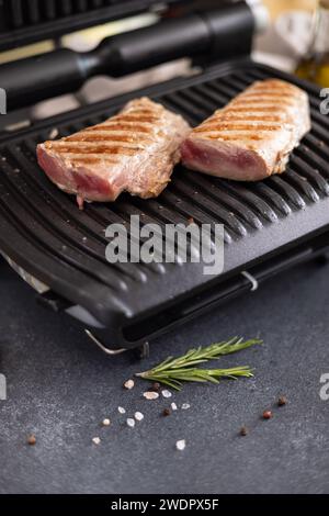 Due pezzi grigliati di filetto di tonno su una griglia elettrica nella cucina domestica Foto Stock