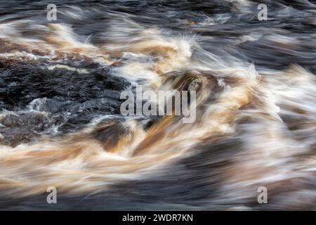 Acqua che scorre velocemente sulle rocce. River Findhorn, Morayshire, Scozia. Esposizione lunga astratta Foto Stock