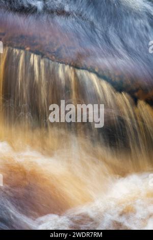 Acqua che scorre velocemente sulle rocce. River Findhorn, Morayshire, Scozia. Esposizione lunga astratta Foto Stock