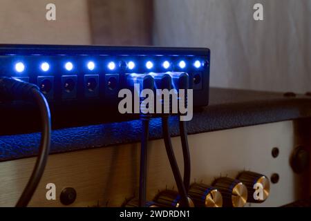 Alimentatore multiplo da 9 volt per pedali di chitarra seduti su un amplificatore Foto Stock