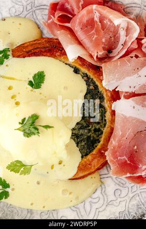 panino di spinaci con salsa al formaggio e prosciutto su un pla Foto Stock