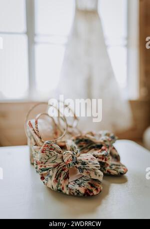 primo piano di scarpe da sposa con abito da sposa sullo sfondo. Foto Stock