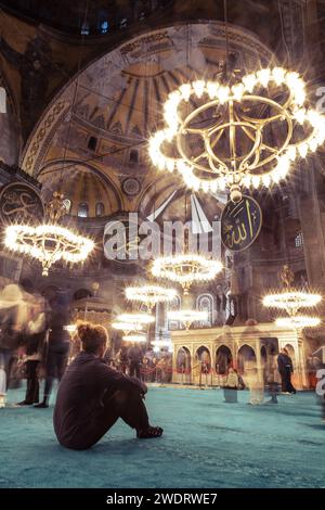 Un uomo seduto su un tappeto verde nella moschea di Santa Sofia Foto Stock