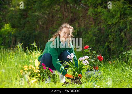 bella, giovane donna che piantava fiori nel terreno. Foto Stock