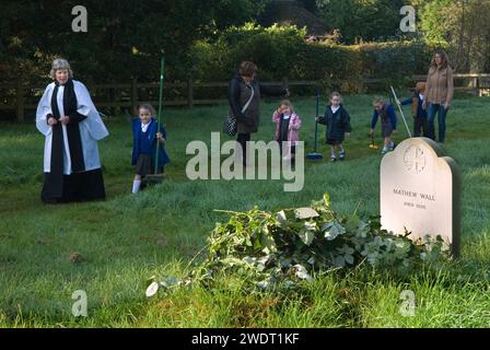 Braughing, Hertfordshire, Inghilterra 1 ottobre 2015. Old Mans Day, il reverendo Julie Gawthrope e i bambini della Jenyns First School intorno alla tomba di Mathew Wall. Brambles è stato posto sulla tomba come indicato nel suo testamento per evitare che il bestiame pascoli sopra di essa. Foto Stock