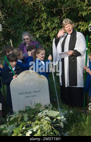 Braughing, Hertfordshire, Inghilterra 1 ottobre 2015. Old Mans Day, il reverendo Julie Gawthrope e i bambini della Jenyns First School intorno alla tomba di Mathew Wall. Brambles è stato posto sulla tomba come indicato nel suo testamento per evitare che il bestiame pascoli sopra di essa. Foto Stock