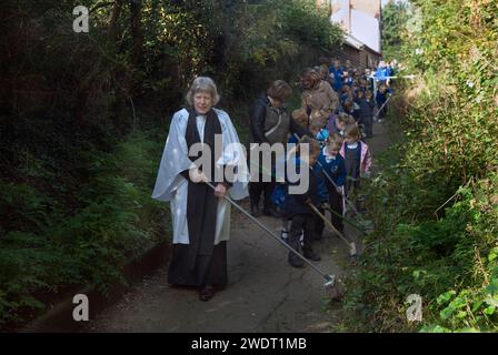 Braughing, Hertfordshire, Inghilterra 1 ottobre 2015. Old Mans Day, la Rev. D Julie Gawthrope che spazia Fleece Lane dal Fleece Inn che conduce alla chiesa di St. Marys the Virgin con l'aiuto dei bambini della prima scuola Jenyns. Inghilterra Regno Unito 2010s HOMER SYKES Foto Stock