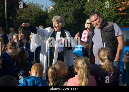 Old Mans Day, Mark Landon con la moneta da una sterlina che pagherà al vicario il Rev'd Julie Gawthrope per aver spazzato Fleece Lane. Come dettato dagli atti, la fattoria un tempo di proprietà di Mathew Wall. Braughing, Hertfordshire, Inghilterra 1 ottobre 2015. Foto Stock