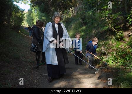 Braughing, Hertfordshire, Inghilterra 1 ottobre 2015. Old Mans Day, la Rev. D Julie Gawthrope che spazia Fleece Lane dal Fleece Inn che conduce alla chiesa di St. Marys the Virgin con l'aiuto dei bambini della prima scuola Jenyns. Inghilterra Regno Unito 2010s HOMER SYKES Foto Stock