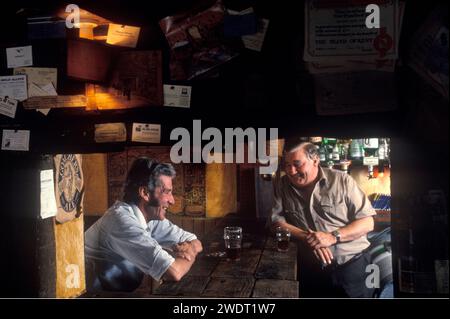 Cliente pubblicano e locale, proprietario che chiacchiera dietro il bar (R) interno del pub del villaggio. Le monete dei clienti sono al bar, gli amici stanno chiacchierando sopra una pinta di birra reale. The Three Chimneys, Biddenden, Kent 1991 90s UK HOMER SYKES Foto Stock