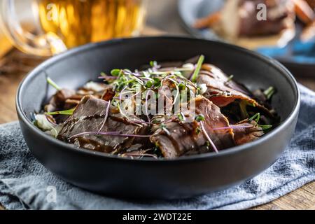 Insalata di manzo arrosto con erbe e salsa balsamica nello stile di una ciotola su un tavolo del ristorante - primo piano. Foto Stock