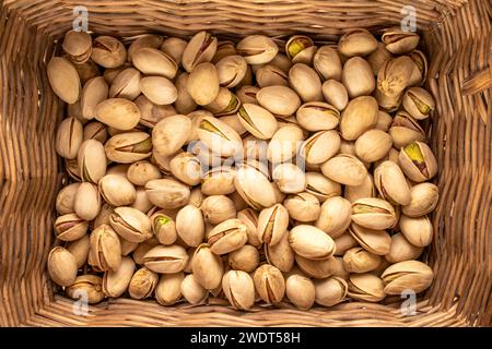 Una piccola quantità di pistacchi deliziosi in un cestino, macro, vista dall'alto. Foto Stock