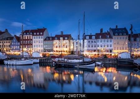 Edifici colorati e barche alte con alberi sul lungomare di Nyhavn al tramonto, canale Nyhavn, Nyhavn, Copenaghen, Danimarca, Europa Foto Stock